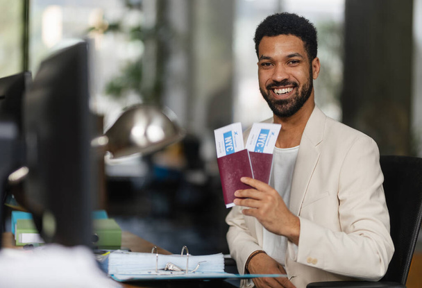 Young happy man holding plane tickets in an office. - Fotografie, Obrázek