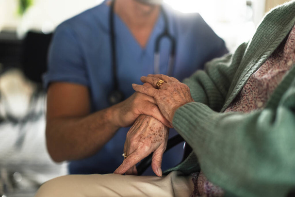 Close up of caregiverr holding hands of his senior client, concept of healthcare and relationships. - Fotó, kép