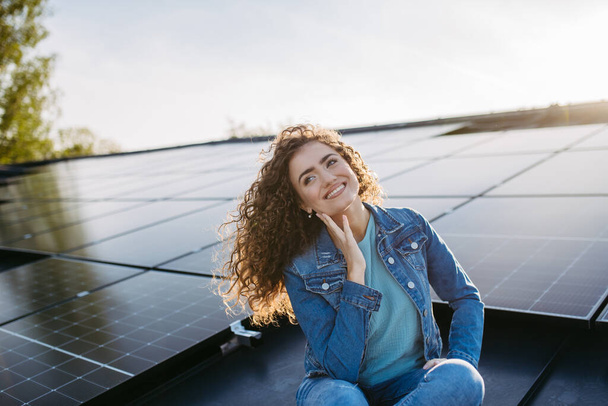 Portrait of young woman, owner on roof with solar panels. - Photo, image
