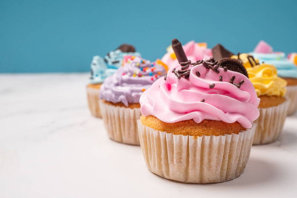 Delicious homemade cupcakes with Colorful cream and topping with candy and Chocolate Cookies. Homemade autumn holiday dessert - Foto, afbeelding