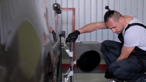 A male car mechanic does a camber. The master works in a car service. 4k video - Filmati, video