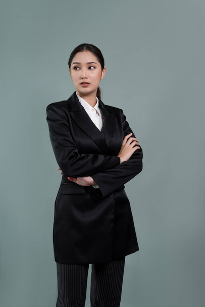 Selbstbewusste junge Geschäftsfrau steht isoliert vor einem Hintergrund und posiert im formellen schwarzen Anzug. Bürokauffrau oder Manager mit intelligentem und professionellem Auftreten. Enthusiastisch - Foto, Bild
