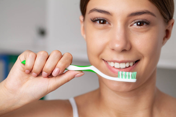 Щаслива леді чистить зуби зубною щіткою стоячи у ванній
. - Фото, зображення