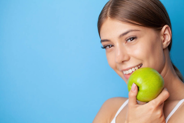 Jeune femme au sourire blanc neige tenant la pomme verte, soins des dents - Photo, image