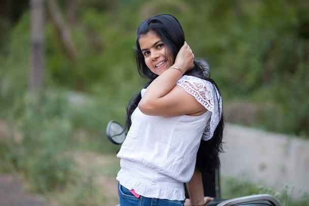 Una joven hermosa india con scooter sonriendo y divirtiéndose - Foto, Imagen
