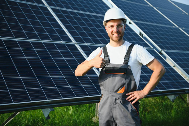 Miespuolinen työntekijä aurinkovoimala aurinkosähköpaneelien taustalla - Valokuva, kuva