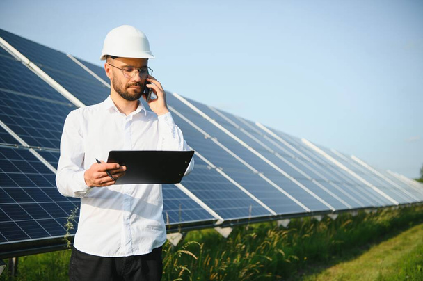 Investidor masculino barbudo positivo contra painéis fotovoltaicos que produzem energia alternativa - Foto, Imagem