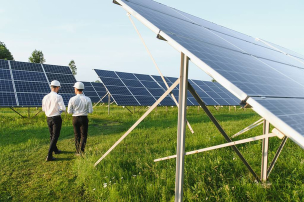 The solar farm(solar panel) with two engineers walk to check the operation of the system, Alternative energy to conserve the world's energy, Photovoltaic module idea for clean energy production - Valokuva, kuva