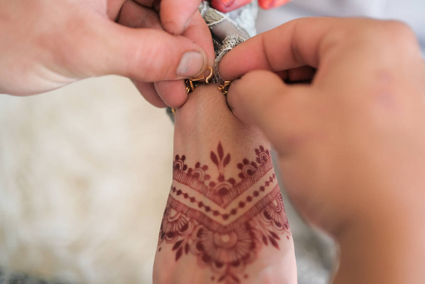 Le marié habille le bracelet de la main de la mariée lors de la cérémonie de mariage malaise en Malaisie. La main des mariées avec du henné - Photo, image