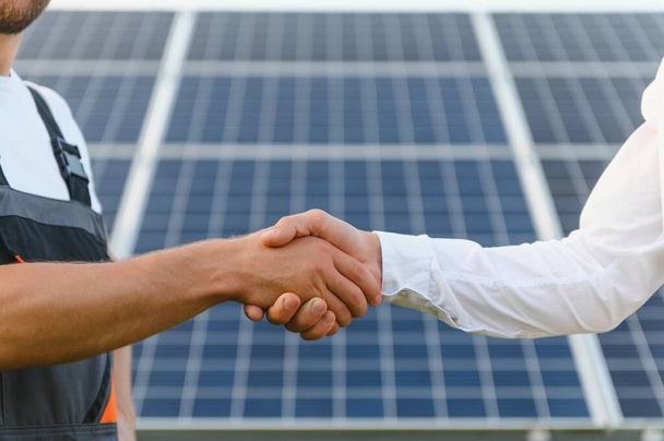 Workers shaking hands on a background of solar panels on solar power plant - Valokuva, kuva