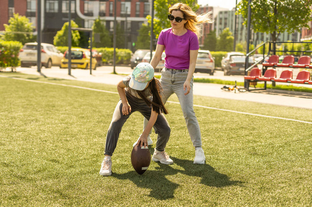 mother and daughter playing american football. - Photo, Image