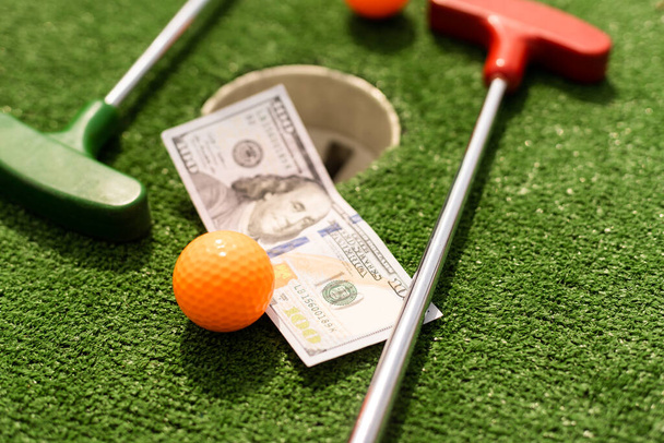 Money, mini golf balls on grass. Concept of sports bet. - Foto, imagen