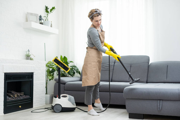 Woman cleaning couch with vacuum cleaner at home. - Fotografie, Obrázek