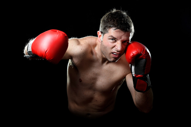 悪質な投げる赤い戦闘手袋でジムに猛烈な男トレーニング ボクシング パンチします。 - 写真・画像