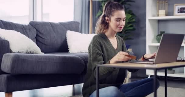 Young woman, laptop and credit card in living room with typing, ecommerce or online shopping for discount. Girl, fintech and computer with password, payment and cybersecurity for deal, sale or budget. - Záběry, video