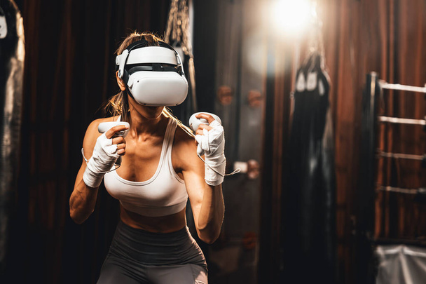 Female boxer training with VR or virtual reality, wearing VR headset with immersive boxing training technique using controller to enhance her skill in boxing simulator. Impetus - Valokuva, kuva