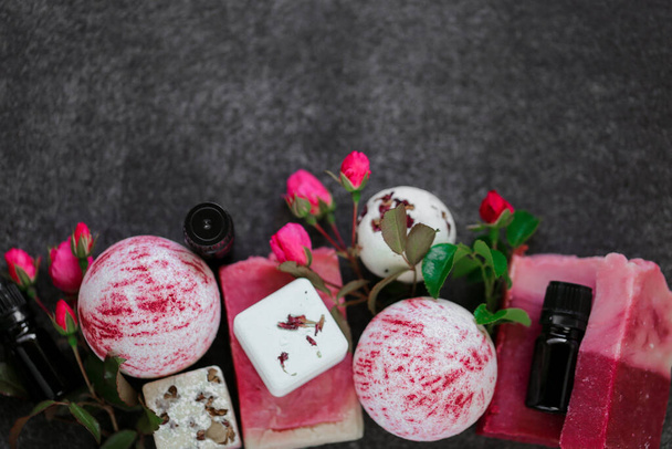 バラエキス配合の化粧品。Badebombs 、花弁のある石鹸、エッセンシャルオイルとピンクのバラの花は黒いスレートの背景にあります。上からの眺めコピースペースバラ油のオーガニックボディ化粧品 - 写真・画像