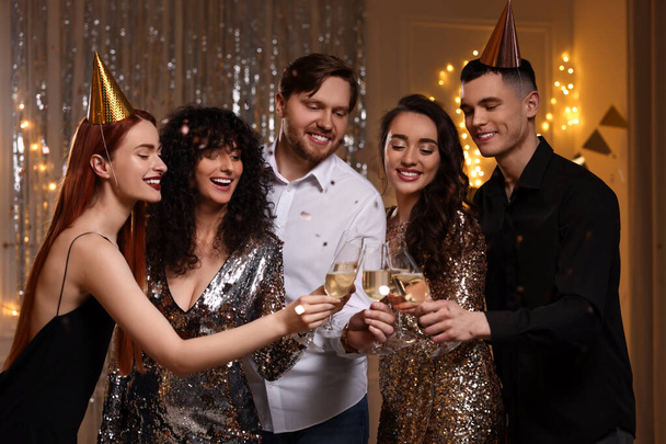 Happy friends clinking glasses of sparkling wine at birthday party indoors - Photo, image