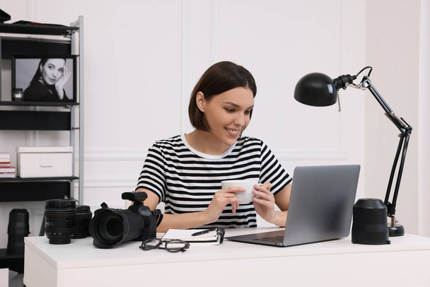 Young professional photographer with camera working on laptop in modern photo studio - Foto, Bild