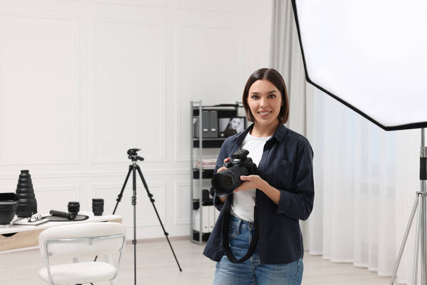 Young professional photographer with camera in modern photo studio, space for text - Zdjęcie, obraz