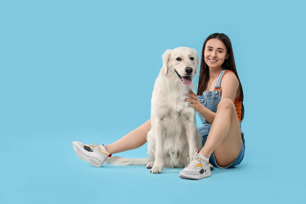 Happy woman with cute Labrador Retriever dog on light blue background. Adorable pet - Foto, imagen