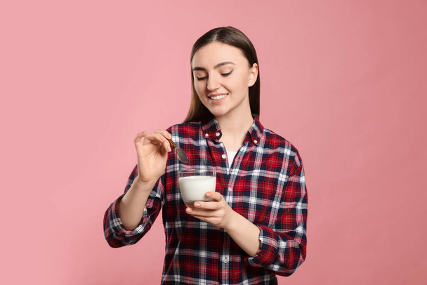 Woman with tasty yogurt on pink background - Фото, зображення