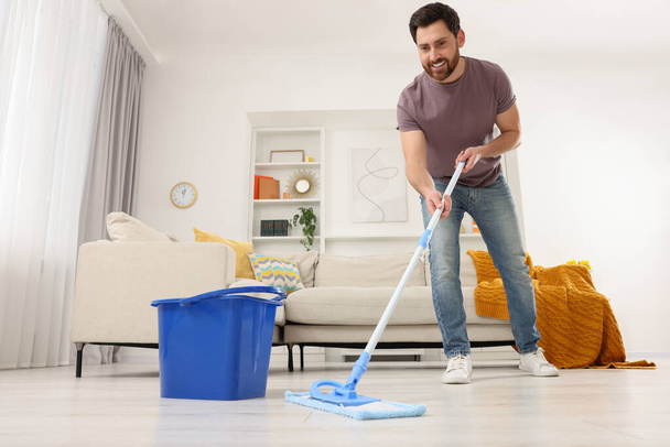 Spring cleaning. Man with mop washing floor at home - Foto, Bild