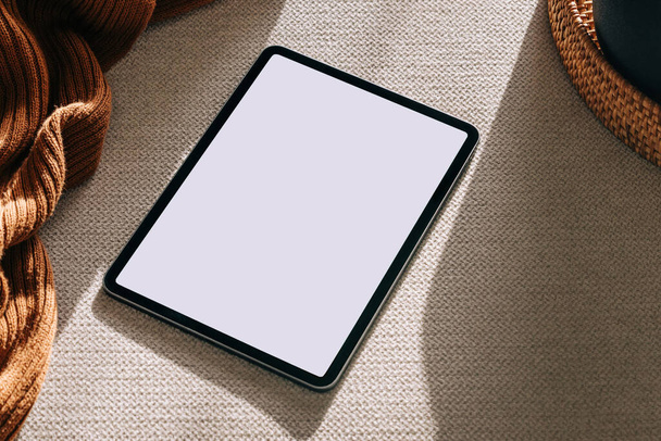 Tablet with white screen on the sofa in natural light. Device mock-up in neutral tones - Photo, image
