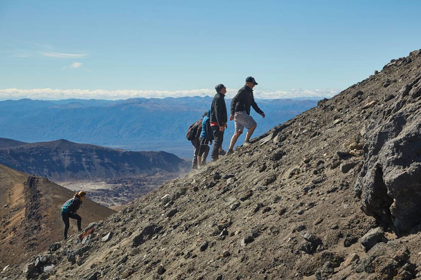 Tongariro Alpine Crossing, Neuseeland - 2. April 2016: Tourist besteigt den steilen, rauen Hang des Mount Ngauruhoe, des berühmten Vulkans, der in den Herr der Ringe-Filmen als Mount Doom bekannt ist - Foto, Bild