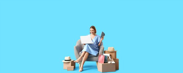 Молодая женщина с ноутбуком и покупками на синем фоне. Интернет-магазины - Фото, изображение
