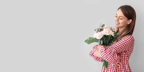 Beautiful young woman with bouquet of carnation flowers on light background. Banner for design - Photo, Image