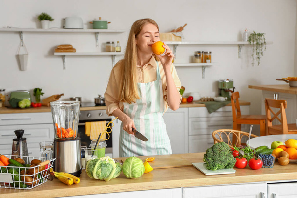 Young woman with orange in kitchen - Photo, Image