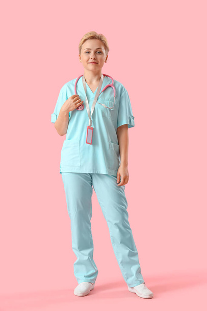 Medizinische Praktikantin mit Stethoskop auf rosa Hintergrund - Foto, Bild