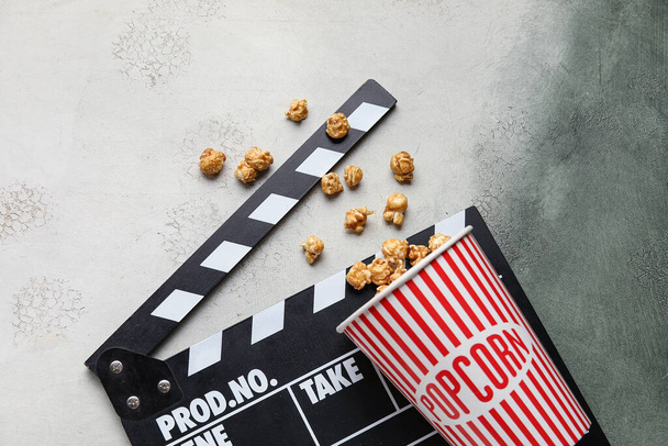 Vödör ízletes popcorn és clapperboard szürke alapon - Fotó, kép