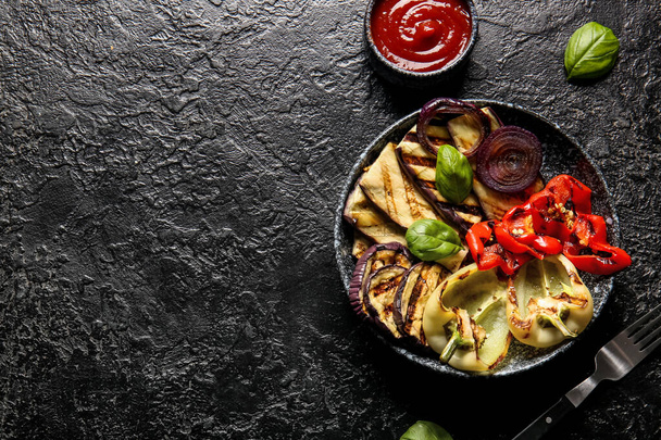 Тарелка с вкусными овощами на гриле и соусом на черном фоне - Фото, изображение