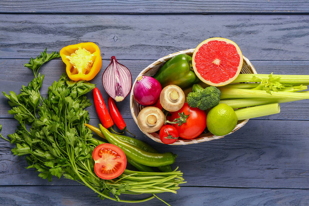 Корзина со свежими спелыми овощами на синем фоне - Фото, изображение