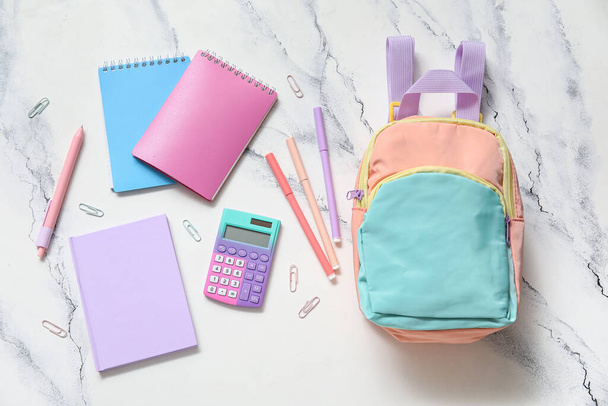 Barevný školní batoh s notebooky, kalkulačkami a značkami na bílém grunge pozadí - Fotografie, Obrázek