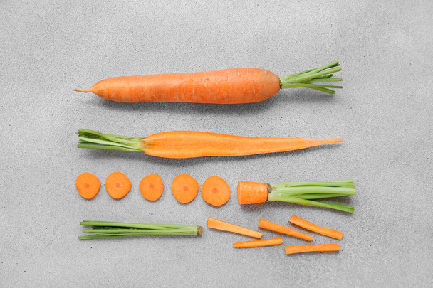 Φρέσκο καρότο και φέτες σε γκρι φόντο - Φωτογραφία, εικόνα