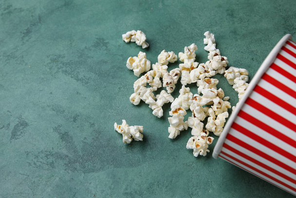Emmer met lekkere popcorn op groene achtergrond - Foto, afbeelding