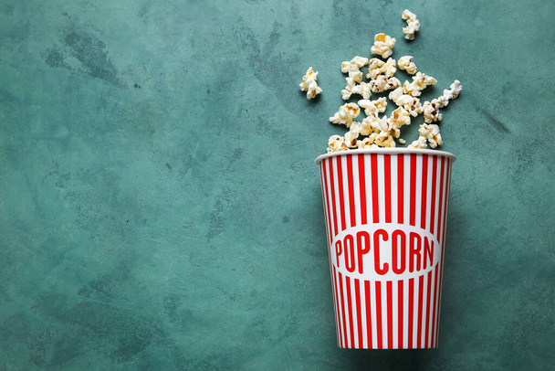 Bucket with tasty popcorn on green background - Photo, Image