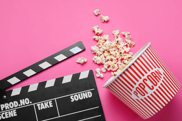 Vödör ízletes popcorn és clapperboard rózsaszín alapon - Fotó, kép