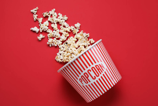 Eimer mit leckerem Popcorn auf rotem Hintergrund - Foto, Bild