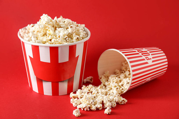 Buckets with tasty popcorn on red background - Foto, afbeelding