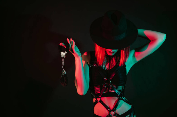 покорная женщина с сексуальным телом в красивом нижнем белье держит в руке наручники для БДСМ-секса с доминированием и подчинением - Фото, изображение
