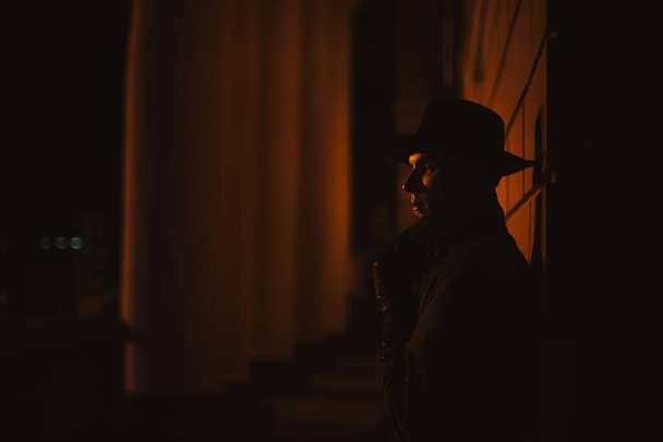 male mafia detective in a hat and raincoat at night in the style of film noir - Фото, изображение