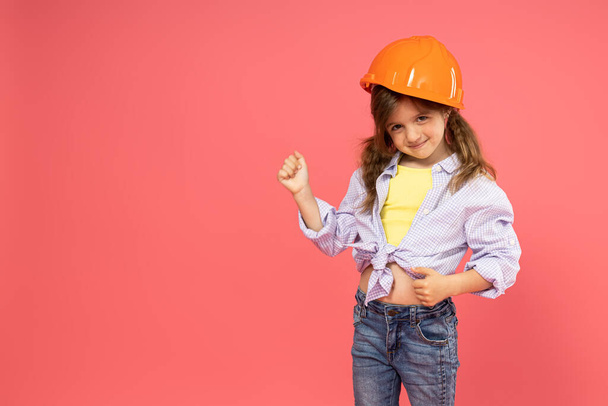 Menina em capacete de construção no fundo rosa, lugar para texto - Foto, Imagem
