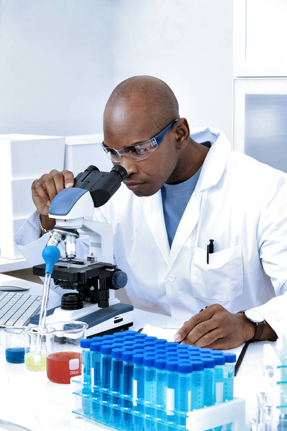 African American Scientist Blick unter das Mikroskop. Wissenschaftliches Labor, Experiment, Medizin, Impfstoffe, Biotechnologieforschung - Foto, Bild