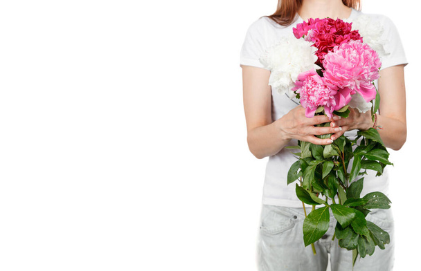 mooie pioenen in de handen van een meisje op een witte achtergrond close-up - Foto, afbeelding