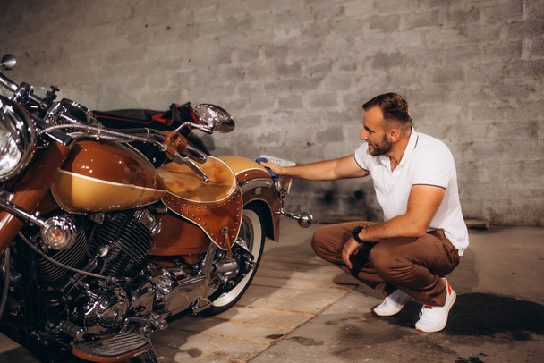 männliche Sammler von Retro-Motorrädern reiben das Motorrad zu einem Glanz. - Foto, Bild