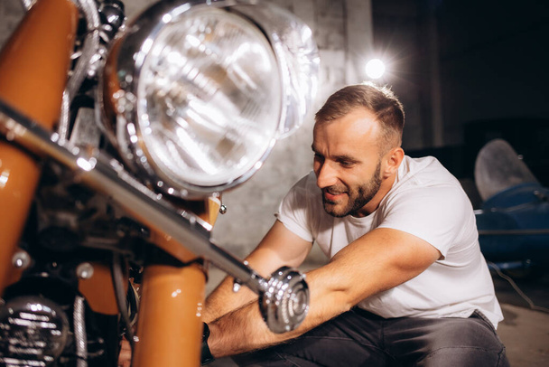 мужчина ремонтирует свой ретро мотоцикл в гараже. - Фото, изображение